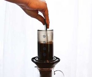 Aeropress with coffee and water and hand stirring contents