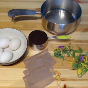 Materials to make coffee dyed eggs--sauce pan, coffee grounds, eggs, nylon squares, rubber bands, flowers, grasses